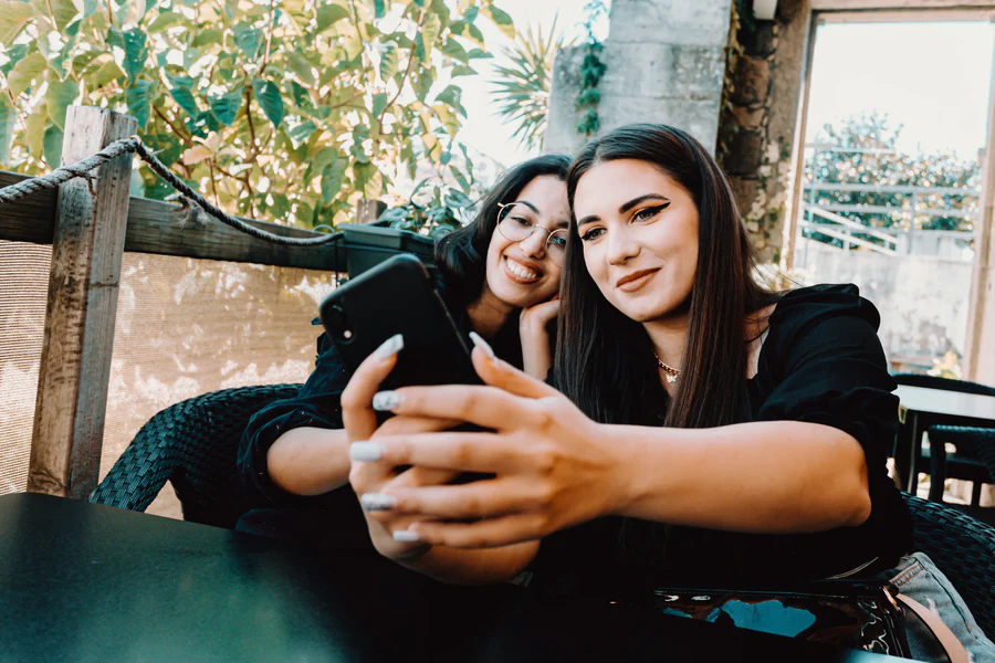 Home two women lean into each other and take a selfie 1 2